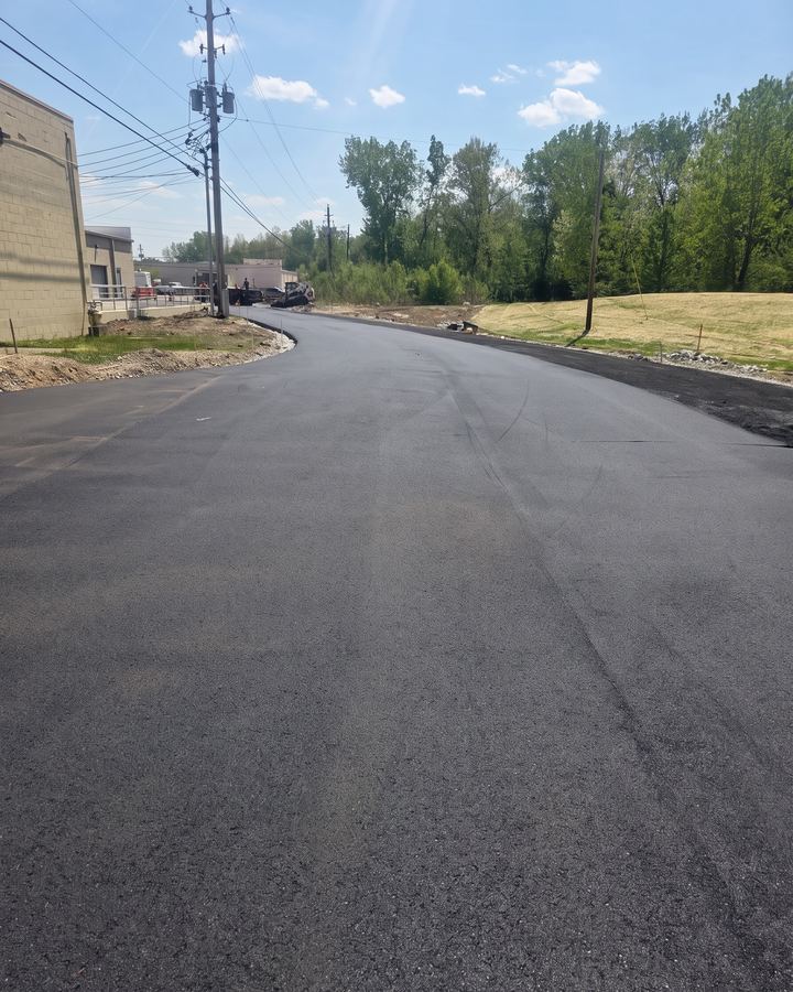 Long freshly paved drive lane beside an industrial building